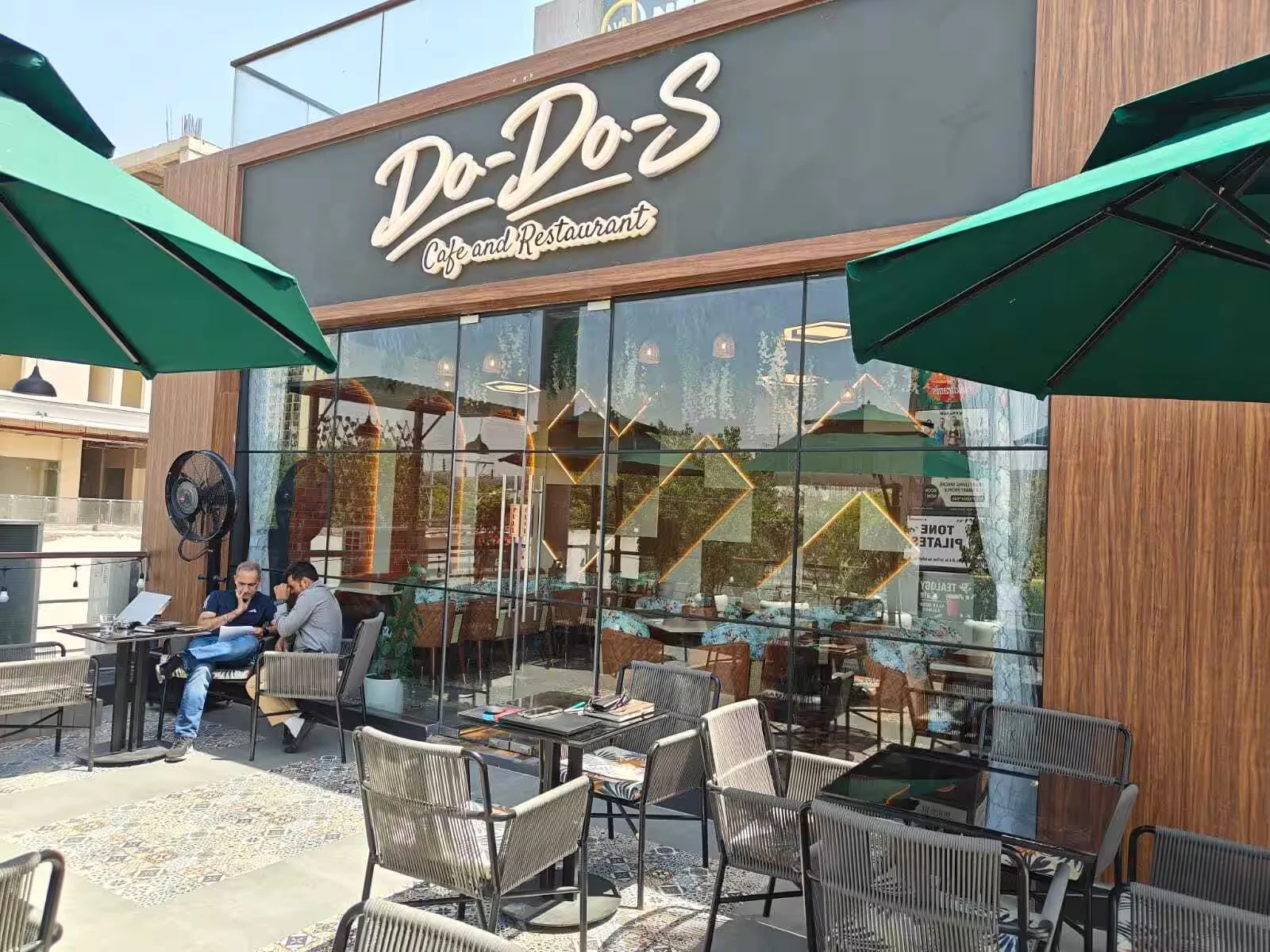 DO-DO-S entrance and outdoor tables under green parasols